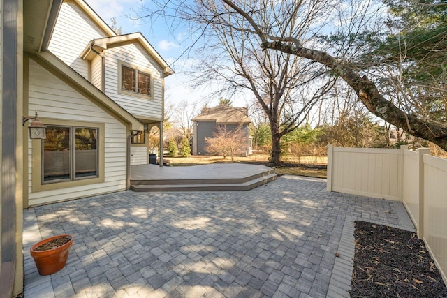 view of patio / terrace featuring fence, a deck, and an outdoor structure