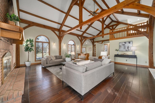 living area featuring a fireplace, high vaulted ceiling, and dark wood finished floors