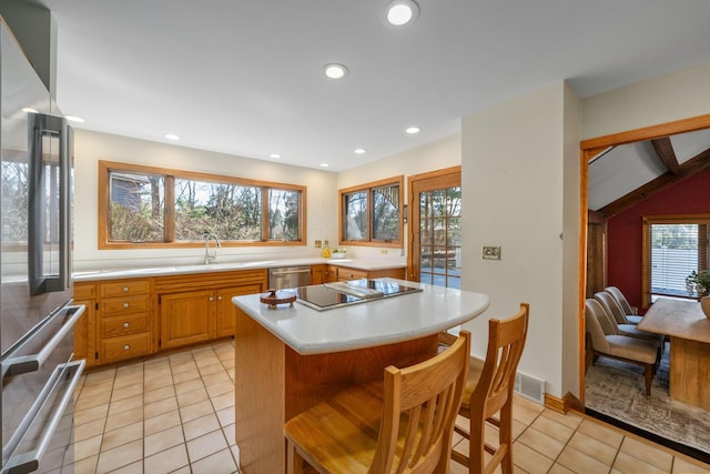 kitchen with light tile patterned floors, light countertops, appliances with stainless steel finishes, and a kitchen bar