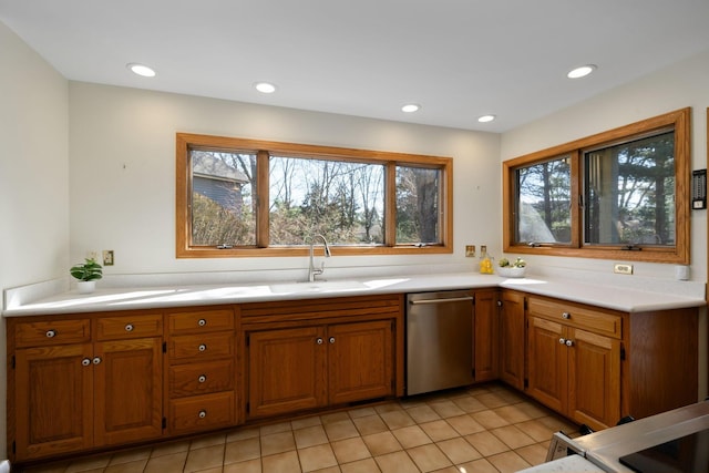 kitchen with stainless steel dishwasher, brown cabinetry, and a sink