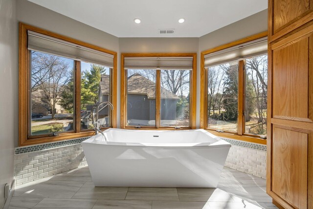 bathroom featuring recessed lighting, a freestanding tub, and visible vents