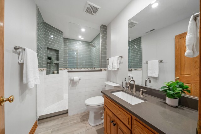 bathroom featuring toilet, visible vents, a walk in shower, and vanity