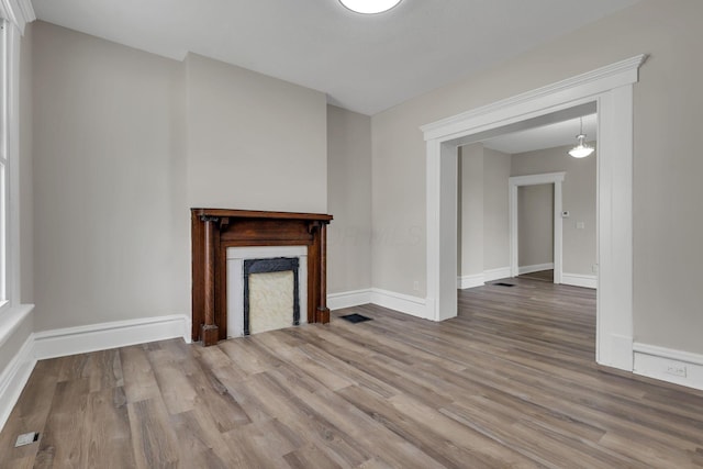 unfurnished living room featuring visible vents, a fireplace, baseboards, and wood finished floors