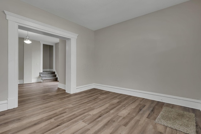 empty room featuring stairway, baseboards, and wood finished floors