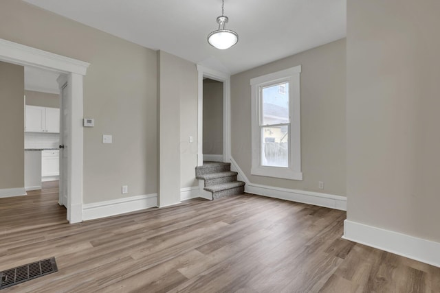 interior space with stairs, light wood finished floors, visible vents, and baseboards