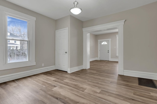 unfurnished room featuring light wood-style flooring, visible vents, and baseboards