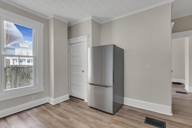 kitchen featuring visible vents, light wood-style flooring, freestanding refrigerator, and baseboards