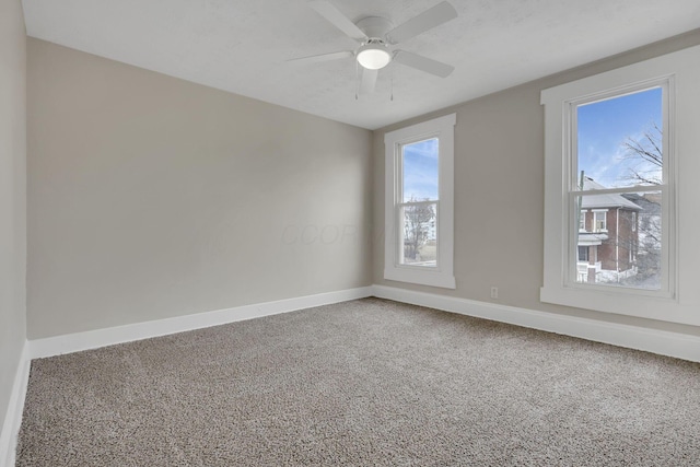 carpeted empty room featuring ceiling fan and baseboards