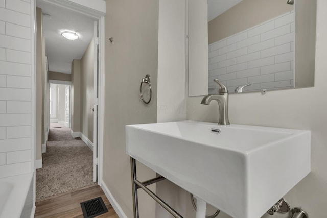 full bathroom featuring baseboards, visible vents, a sink, and wood finished floors