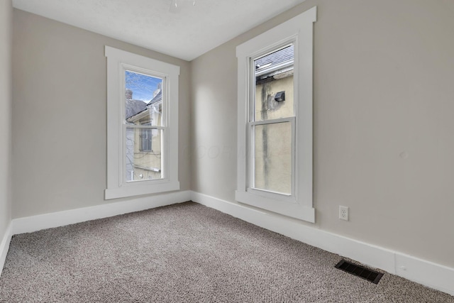 empty room featuring carpet flooring, visible vents, and baseboards