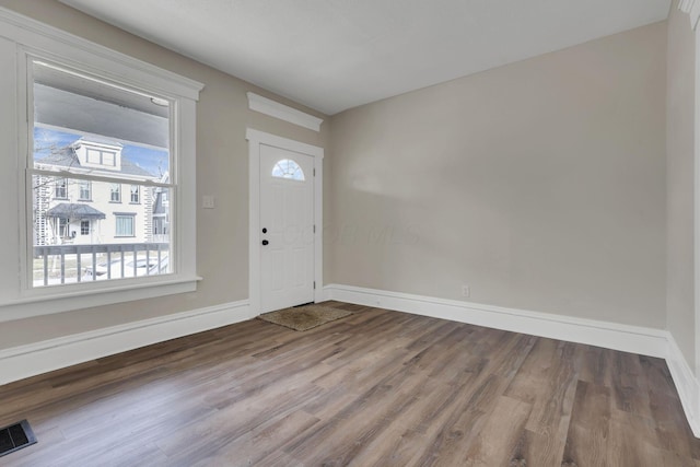 foyer entrance with a healthy amount of sunlight, visible vents, baseboards, and wood finished floors