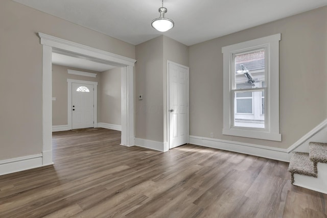 foyer featuring a healthy amount of sunlight, baseboards, stairway, and wood finished floors