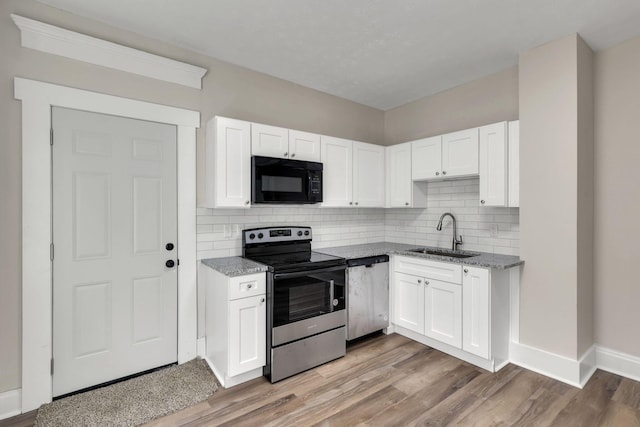 kitchen with appliances with stainless steel finishes, white cabinetry, a sink, and light stone counters