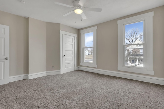 carpeted spare room featuring a ceiling fan, a healthy amount of sunlight, and baseboards