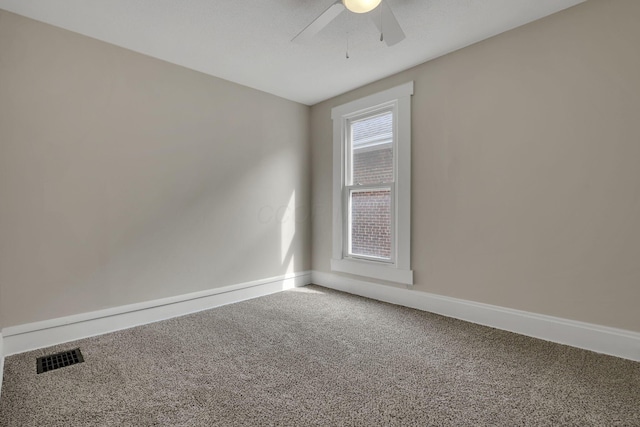 carpeted empty room featuring visible vents, ceiling fan, and baseboards