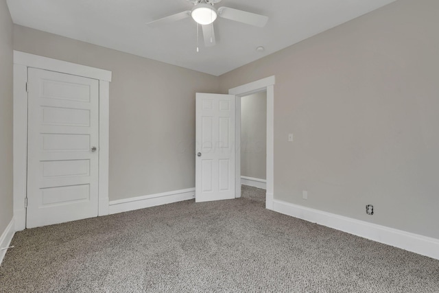 carpeted empty room with baseboards and a ceiling fan