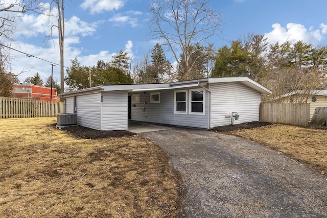 back of house featuring driveway, fence, an attached carport, and cooling unit