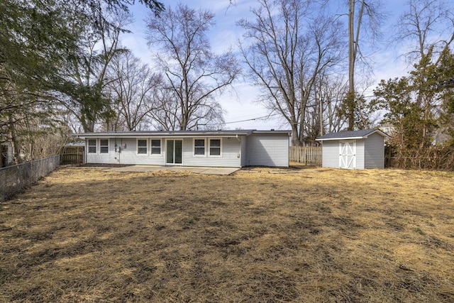 rear view of house with an outbuilding, a storage unit, a patio area, and a fenced backyard