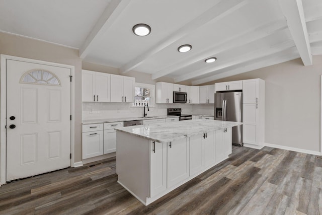 kitchen with appliances with stainless steel finishes, a sink, white cabinets, and a center island