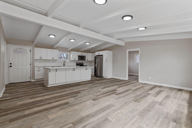 kitchen featuring tasteful backsplash, white cabinets, appliances with stainless steel finishes, open floor plan, and light countertops