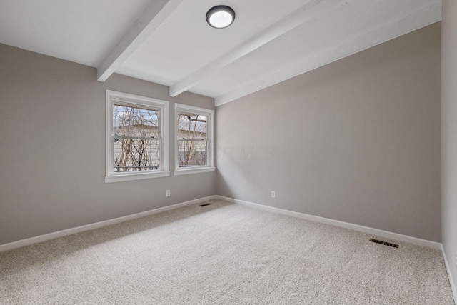 spare room with carpet floors, visible vents, baseboards, and beamed ceiling