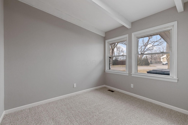 carpeted empty room with baseboards, visible vents, and beamed ceiling