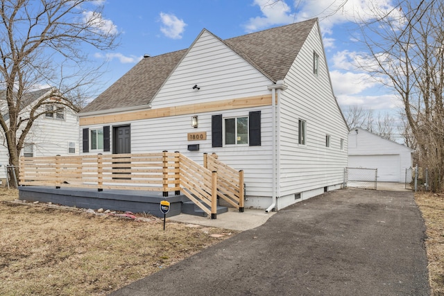 view of front of home featuring a shingled roof, an outbuilding, a wooden deck, and a garage