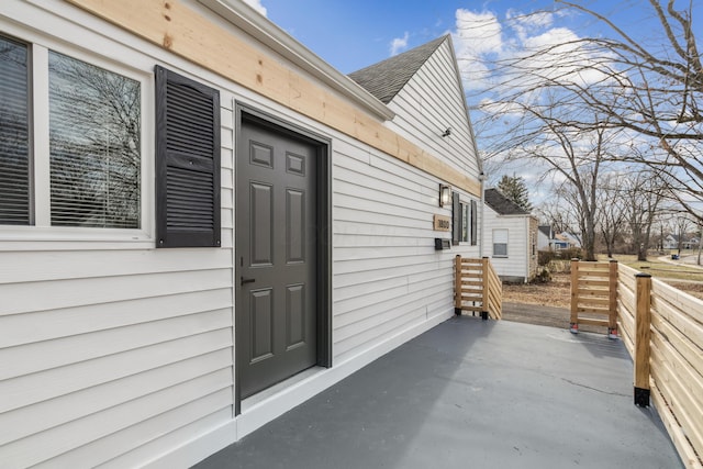 doorway to property with a patio and roof with shingles