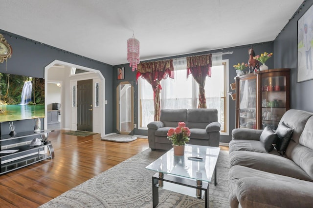 living room with arched walkways and wood finished floors