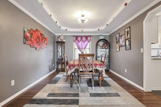 dining space with a tray ceiling, arched walkways, dark wood-type flooring, a chandelier, and baseboards