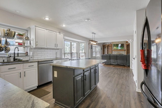 kitchen with white cabinets, dishwasher, open floor plan, freestanding refrigerator, and a sink