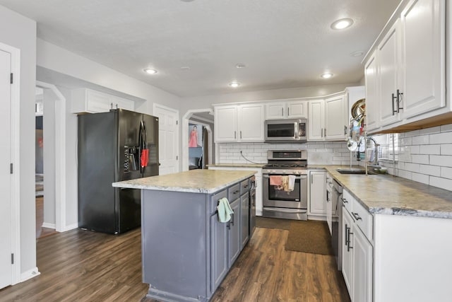 kitchen with appliances with stainless steel finishes, dark wood finished floors, white cabinetry, and a sink