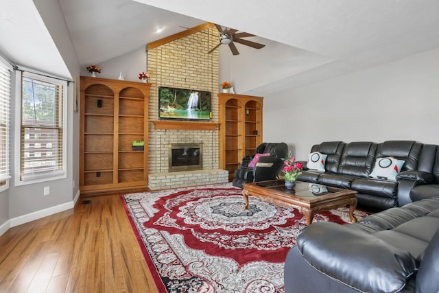 living room with a fireplace, lofted ceiling, ceiling fan, wood finished floors, and baseboards