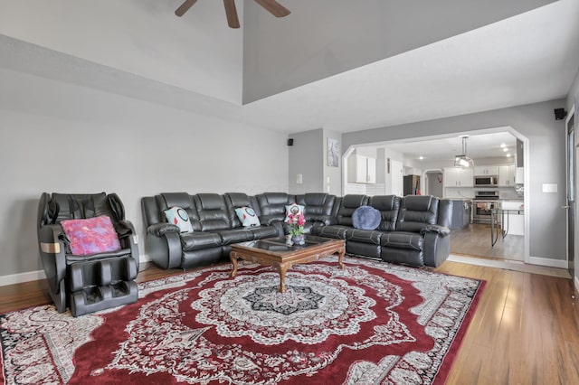 living area with a ceiling fan, light wood-type flooring, and baseboards