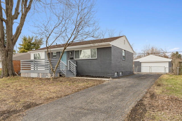 view of front of house featuring a detached garage, an outbuilding, a gate, fence, and brick siding