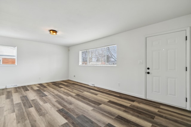 spare room with baseboards, visible vents, and wood finished floors