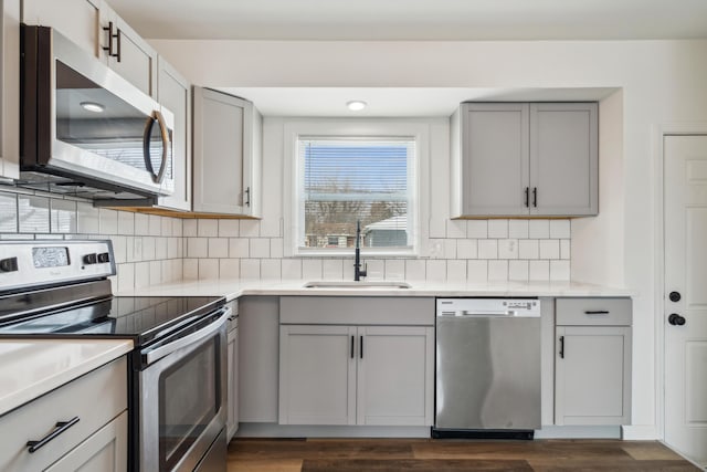 kitchen featuring a sink, light countertops, appliances with stainless steel finishes, gray cabinets, and tasteful backsplash