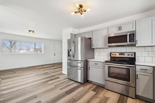 kitchen featuring appliances with stainless steel finishes, gray cabinets, and decorative backsplash