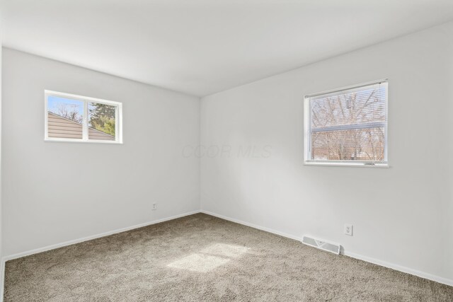 carpeted spare room featuring visible vents and baseboards