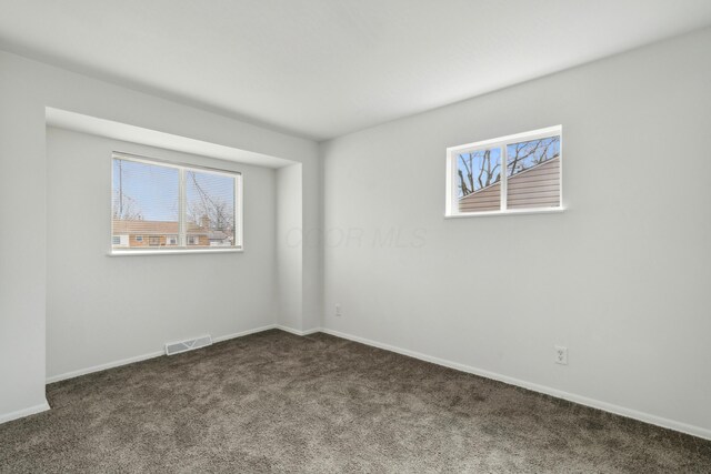 unfurnished room featuring carpet, plenty of natural light, visible vents, and baseboards