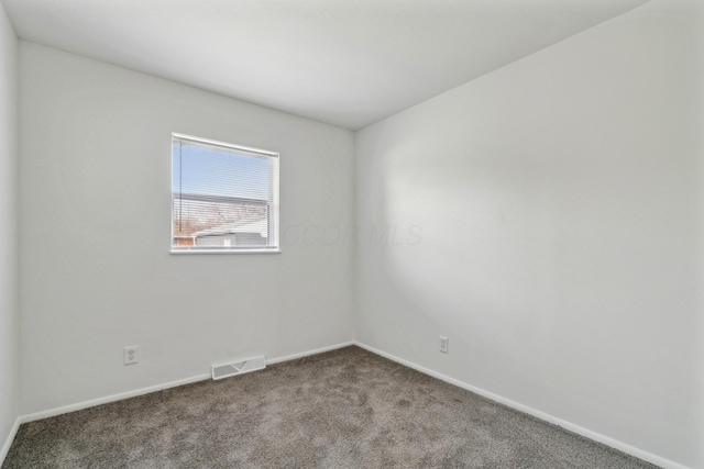 spare room featuring carpet floors, visible vents, and baseboards