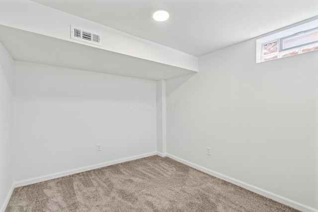 spare room with carpet floors, visible vents, and baseboards