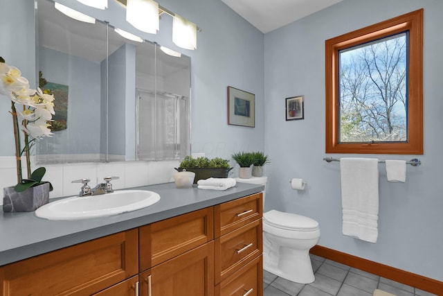 bathroom with toilet, vanity, baseboards, tile patterned floors, and a shower with door