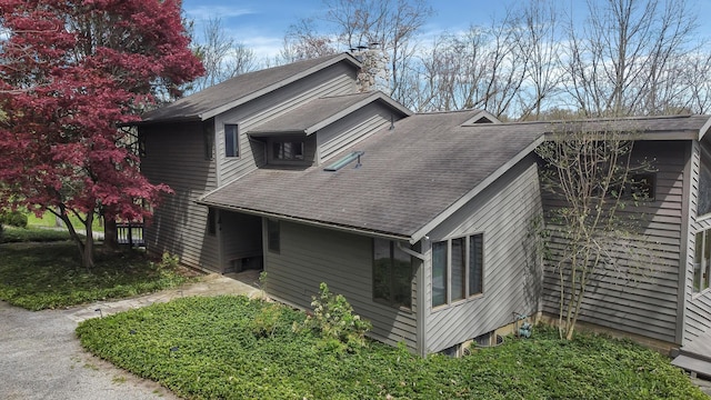 view of side of property with a shingled roof and a chimney