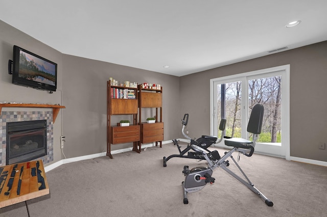 workout room with carpet, a tiled fireplace, visible vents, and baseboards