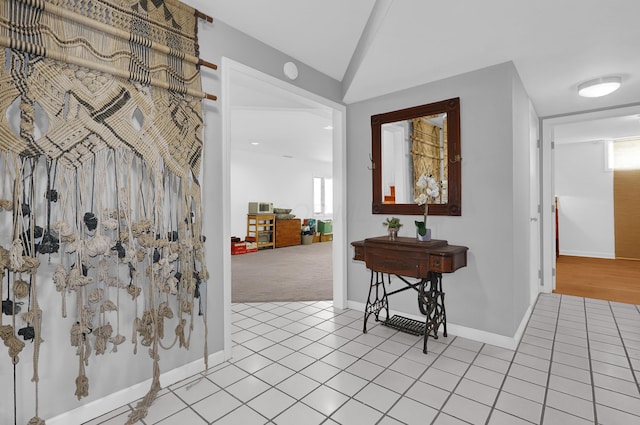 entrance foyer featuring baseboards, vaulted ceiling, and light tile patterned flooring