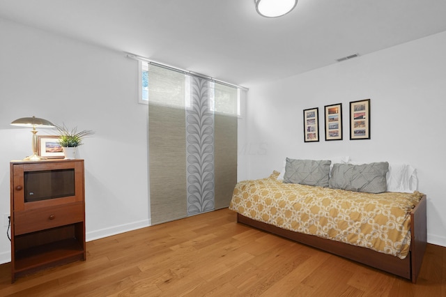 bedroom featuring visible vents, baseboards, and wood finished floors