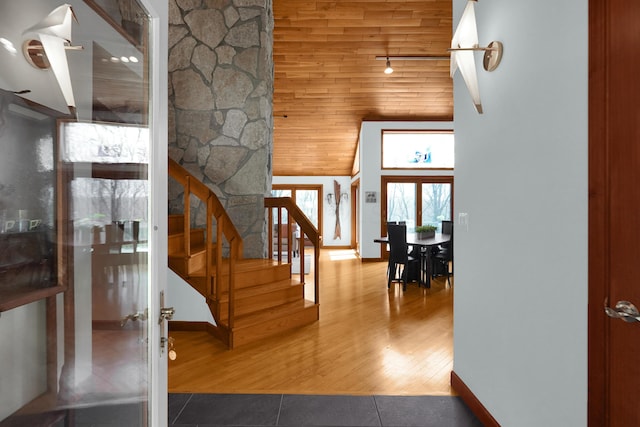 foyer entrance featuring a towering ceiling, stairs, baseboards, and wood finished floors