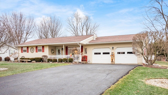 ranch-style home featuring covered porch, driveway, a front yard, and an attached garage