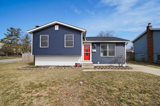 tri-level home featuring entry steps, a front lawn, fence, and roof with shingles